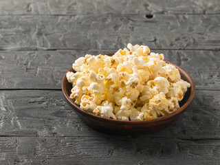 Popcorn in a clay bowl on a black wooden table.