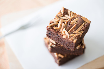 Close up sweet chocolate brownie with almond topping, selective focus