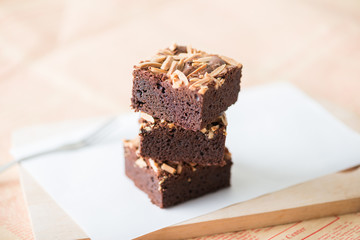 Close up sweet chocolate brownie with almond topping, selective focus