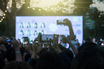 Fan club people taking photographs by smart phone during music entertainment public concert outdoor in evening time, Musical and concert concept