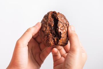 Close up hand holding sweet cookies chocolate brownie on white background, selective focus