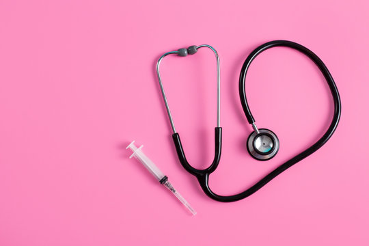stethoscope and syringe on pink pastel background