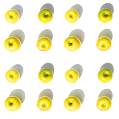 top view of sixteen yellow Granny Smith apples on a white surface
