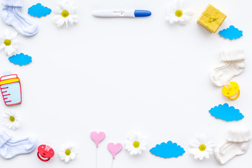 Pregnancy and preparation for childbirth. Pregnancy test near booties and child accessories on white background top view copy space