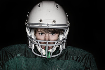 Low key harsh flash image of a boy in a football uniform