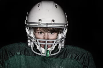 Poster Low key harsh flash image of a boy in a football uniform © soupstock