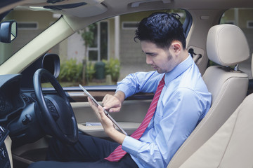 Man driving checks digital tablet for locating an address