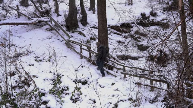 Man goes next to forest along old wooden fence in snow - (4K)