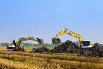 Naklejka premium excavator backhoes are working in the digging a soil to adjust the postharvest areas in the rice fields. agriculture machinery fo the modern agriculture industry.