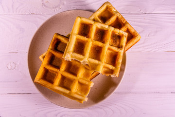 Ceramic plate with belgian waffles on wooden table. Top view