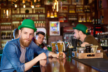 Waist-up portrait of handsome bearded man wearing denim shirt and green bowler hat posing for...