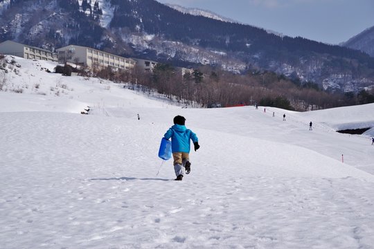 スキー場でソリ遊びをする子供