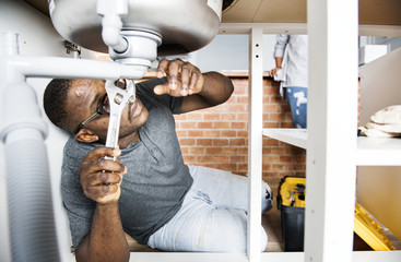 Plumber man fixing kitchen sink - obrazy, fototapety, plakaty