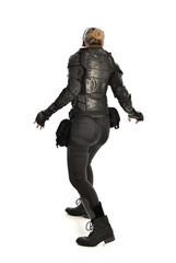 full length portrait of female  soldier wearing black  tactical armour  facing away from camera, isolated on white studio background.