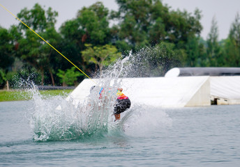 Wake boarding rider jumping trick with water splash in wake park, active extreme sport for healthy ,recreation, hobby or adventure