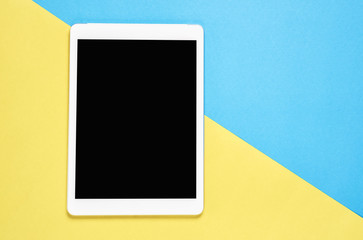Top view, Modern workplace with tablet placed on a pastel yellow background. Copy space suitable for use in graphics.