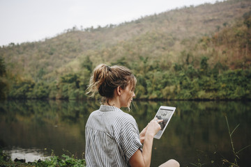 Woman alone in nature using a digital tablet internet connection and travel concept - obrazy, fototapety, plakaty