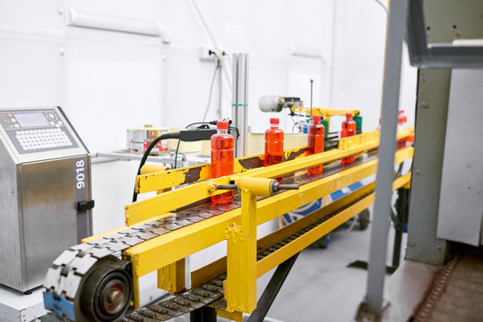 Interior of modern sport nutrition factory: conveyor belt with bottles, white walls, no people
