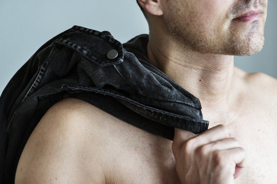 Close up of naked man with his clothes slinging on his shoulder