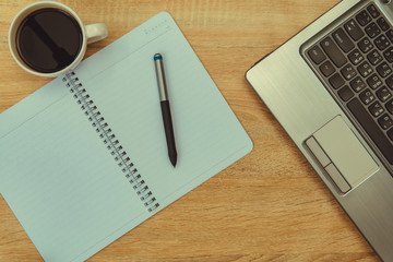 Laptop computer or notebook, note and cup of coffee on working table with copy space top view.