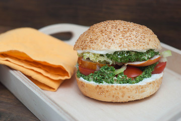 Fast Food. Homemade Hamburger in Wooden box, with fresh Vegetables on rustic Wooden Background with copy Space. Orange Napkin.