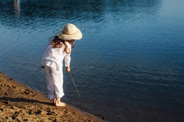 Cute fashionable girl in hat posing near the lake