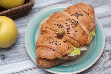 Croissant Sandwich with Tomatoes, Fresh Vegetables, Green Olive on Wooden Textured Grey Background. top view.