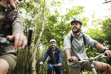 Group of friends ride mountain bike in the forest together