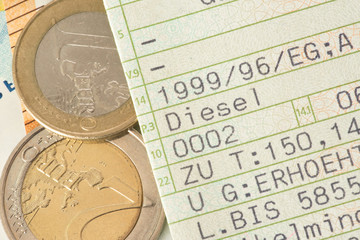 Ein Fahrzeugschein für ein Diesel Auto und Euro Münzen