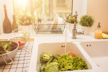 Vegetables lie in the sink near the window