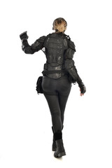 full length portrait of female  soldier wearing black  tactical armour  facing away from camera, isolated on white studio background.