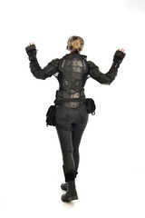 full length portrait of female  soldier wearing black  tactical armour  facing away from camera, isolated on white studio background.