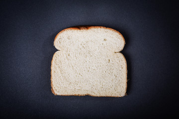 One slice of white sandwich bread on a gray background