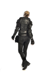 full length portrait of female  soldier wearing black  tactical armour  facing away from camera, isolated on white studio background.