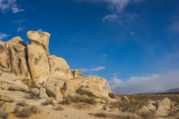 Stack of sandstone boulders stand in the bright light of a hot desert day.