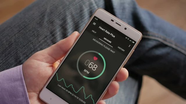 Man Looking At Health Monitoring App On Smartphone. Monitoring the heart pulse with a health application on smartphone.