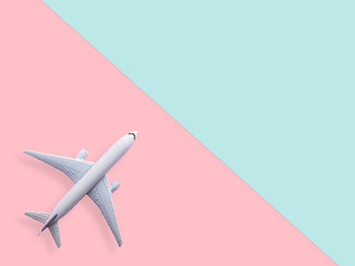 flat lay of white plane model on pastel blue and pink color background with copy space. travel and vacation concept