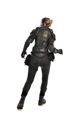 full length portrait of female  soldier wearing black  tactical armour  facing away from camera,...