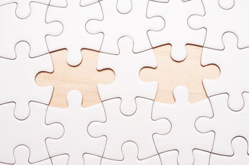 Fototapeta premium White blank puzzle with 2 pieces missing on wooden board with copy space.