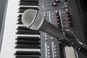 Close up of microphone with electric keyboard piano in background