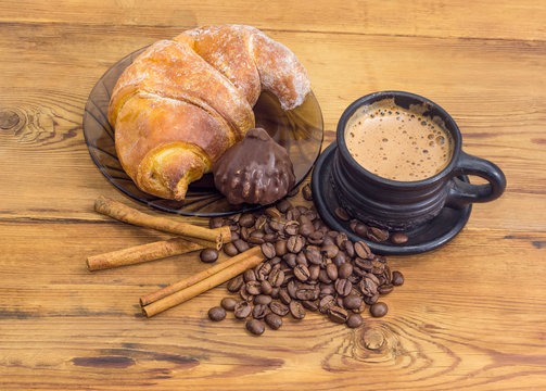 Coffee in black ceramic cup, croissant and chocolate truffle