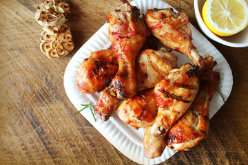 Grilled chicken legs on white plate .Rustic dinner background