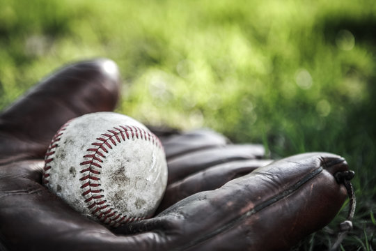 Vintage baseball glove and ball on grass. Very shallow depth of focus