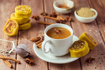 Indian tea masala with spices in white cup, Indian food on wooden table
