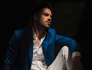 side view of a dramatic man sitting in studio