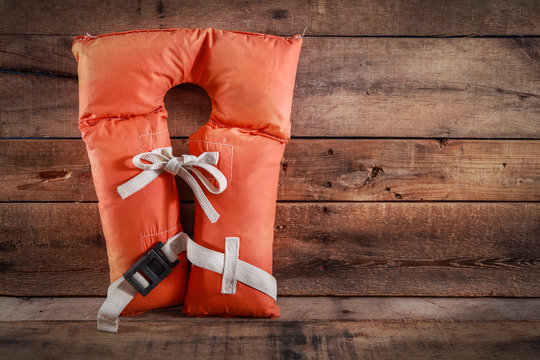 Old vintage life vest on a wooden background
