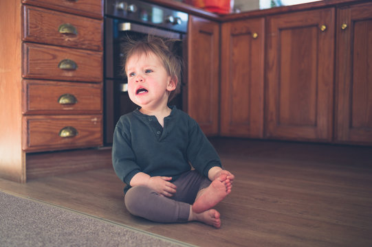 Sad little toddler on kitchen floor