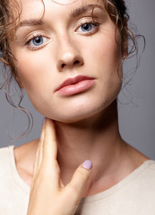 Beauty portrait of young woman. Brunette girl with bright blue eyes and day female makeup on gray background