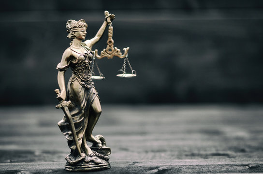 Scales of Justice, Justitia, Lady Justice on a black wooden background.