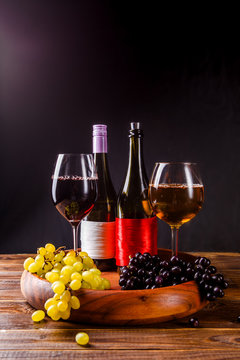 Picture of wine glass with wine, grape black, green on wooden tray on table